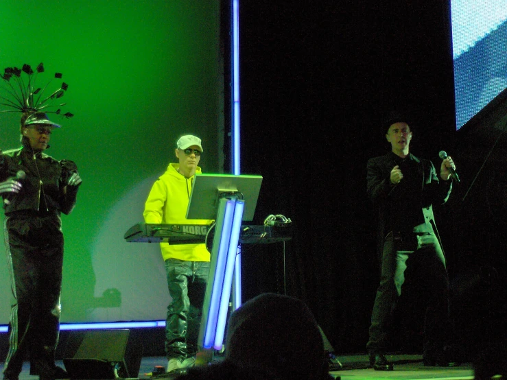 two men are standing on a stage, one in the process of presenting a computer