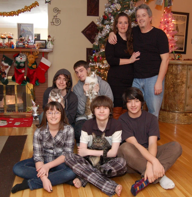 a group of people and their cat in front of a christmas tree