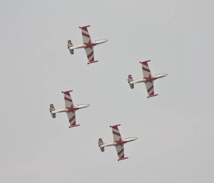 four airplanes in the air with some red and white