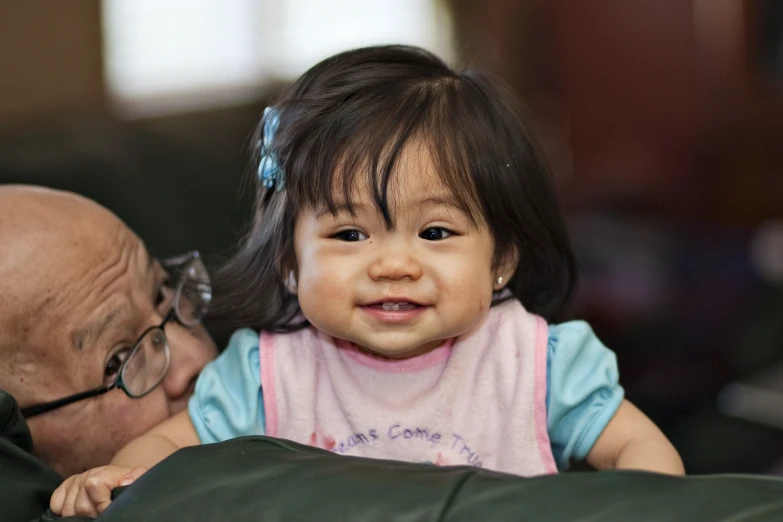 a small child wearing eye glasses smiling at an older person