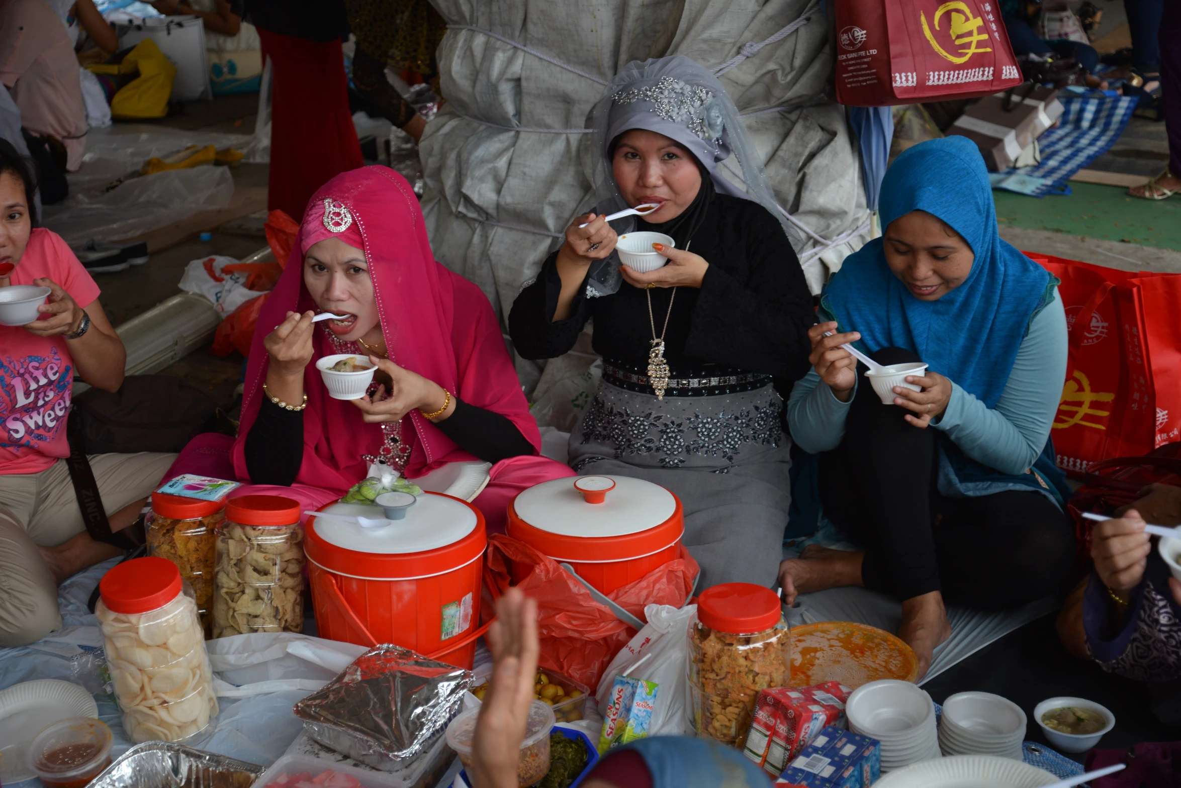 three women sit eating at a table covered in bowls