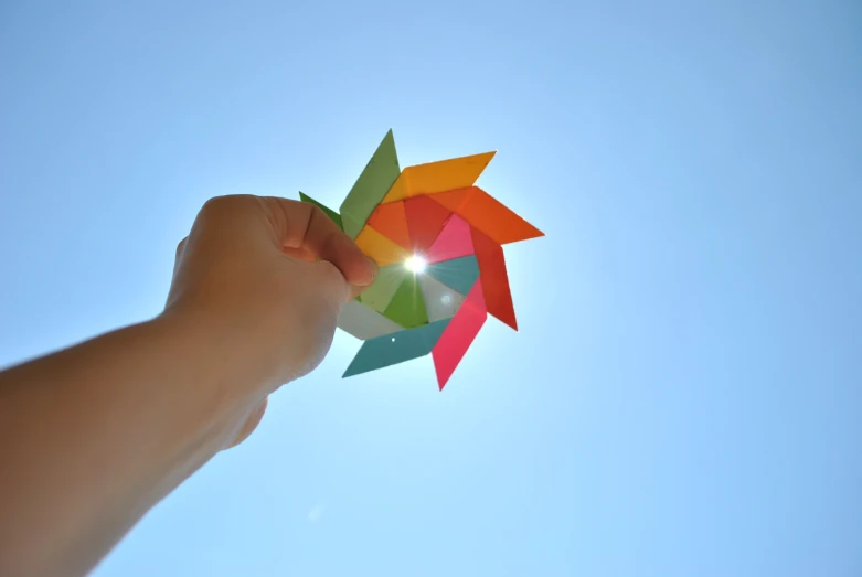 the colorful kite is being held up by a hand