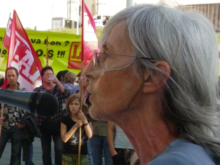 a man on a microphone speaking into people holding flags