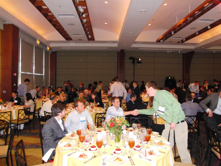 a crowd of people in a large dining room, some eating