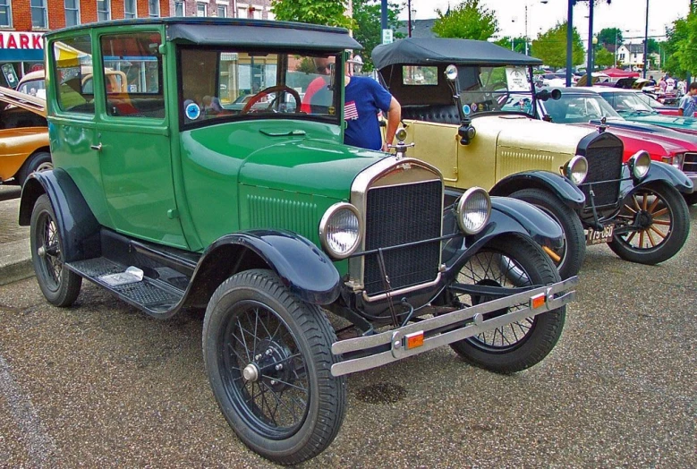 a green antique car is parked in front of a brown car