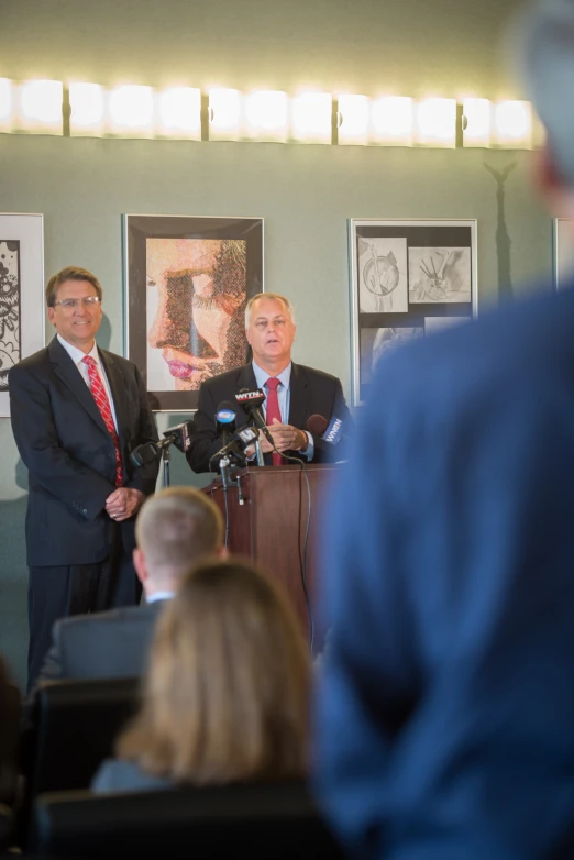 two men are standing at a podium during a press conference