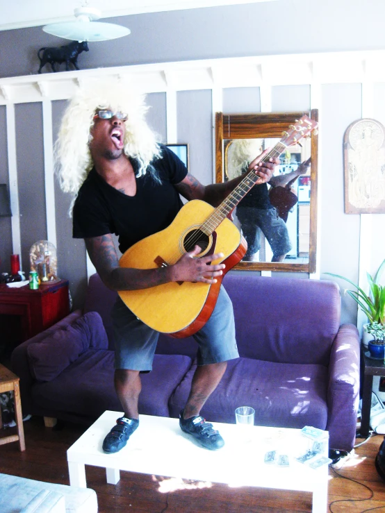 a man with a guitar is standing in the living room