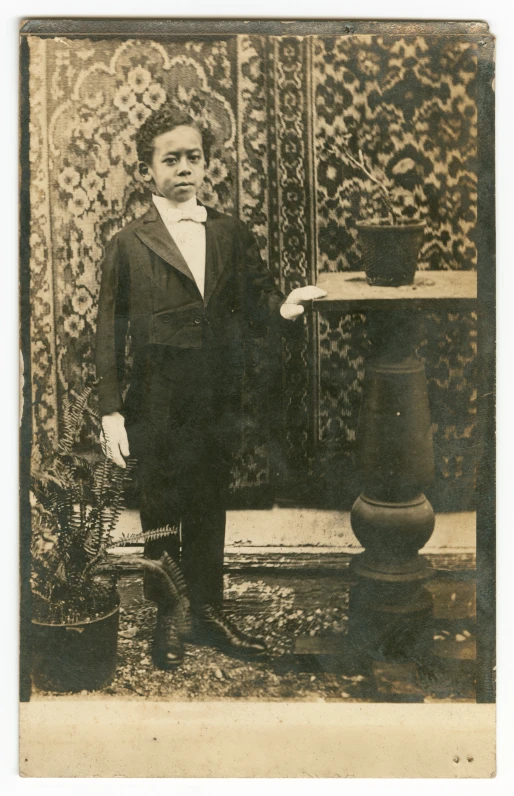 an old fashion po shows a boy standing in front of a fireplace