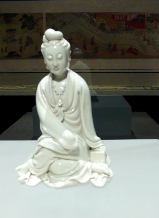 white statue of buddha sitting in front of a painting