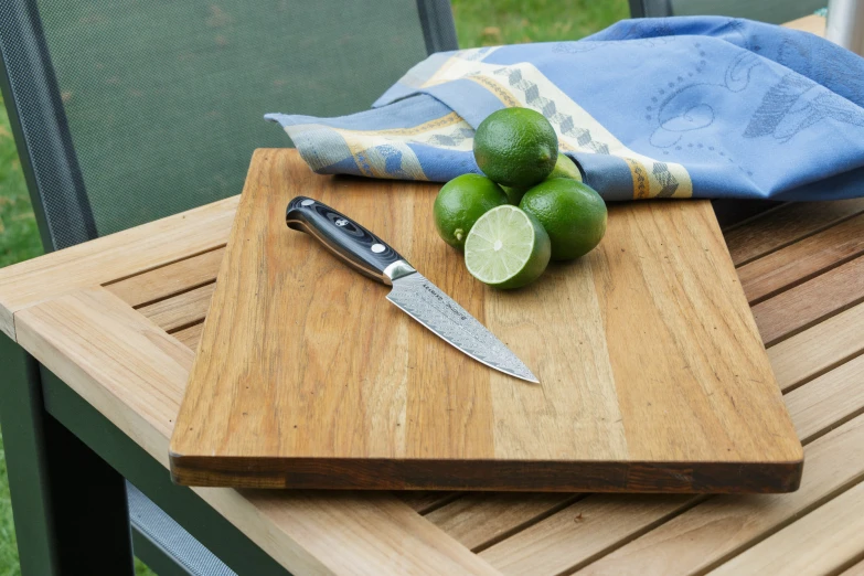 a  board with a knife and limes on it