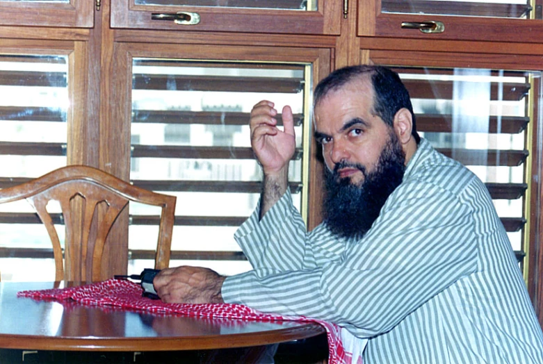 an old man sitting in front of a table holding a glass