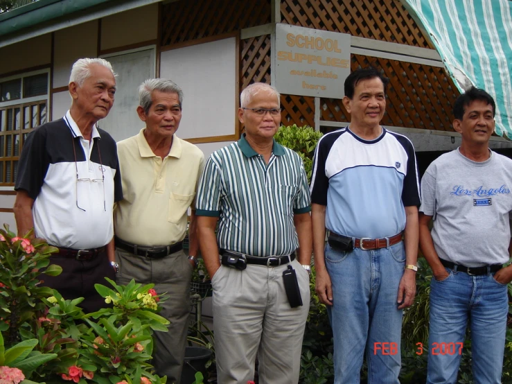 four men are standing in front of a house