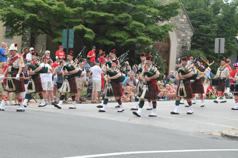 several pipe players, some wearing green and white, on the street