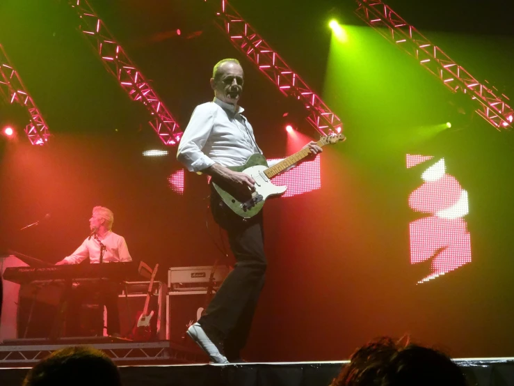 a man playing guitar in front of some lights