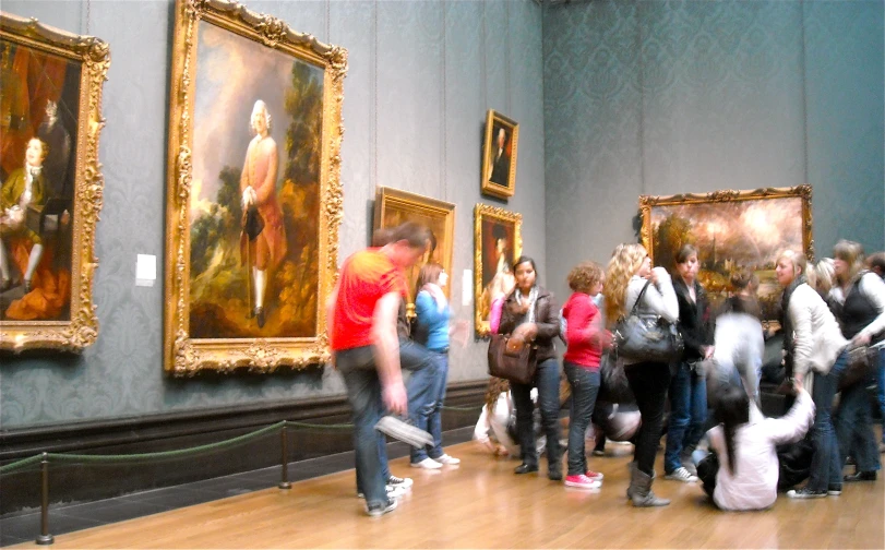 many people are looking at some paintings in an old museum