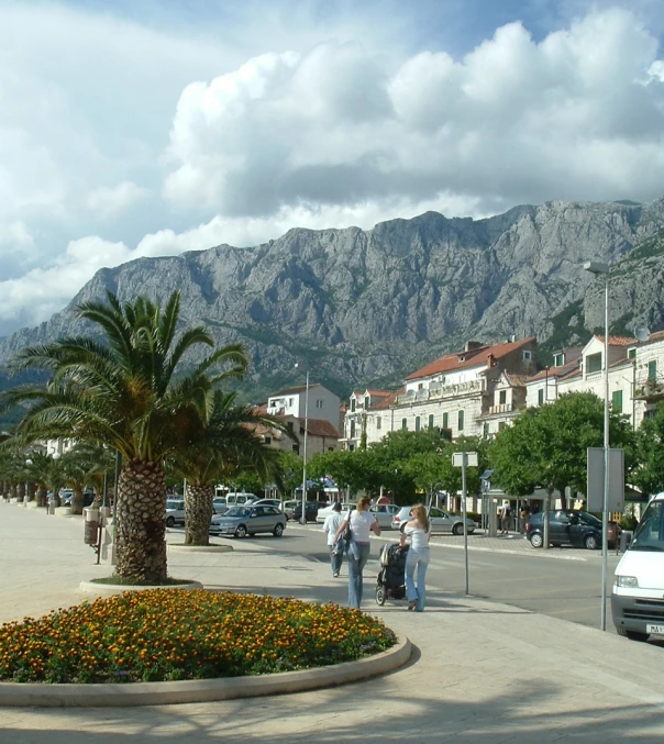 several people standing around on the street near some mountains