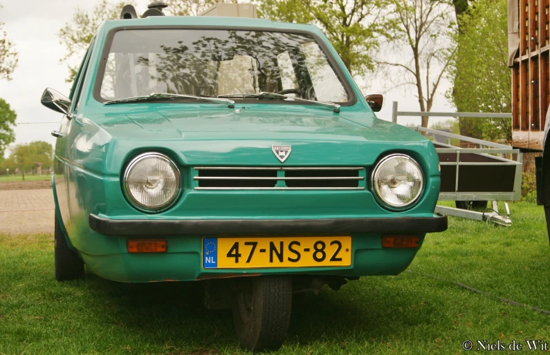 a green car sitting on top of a lush green field