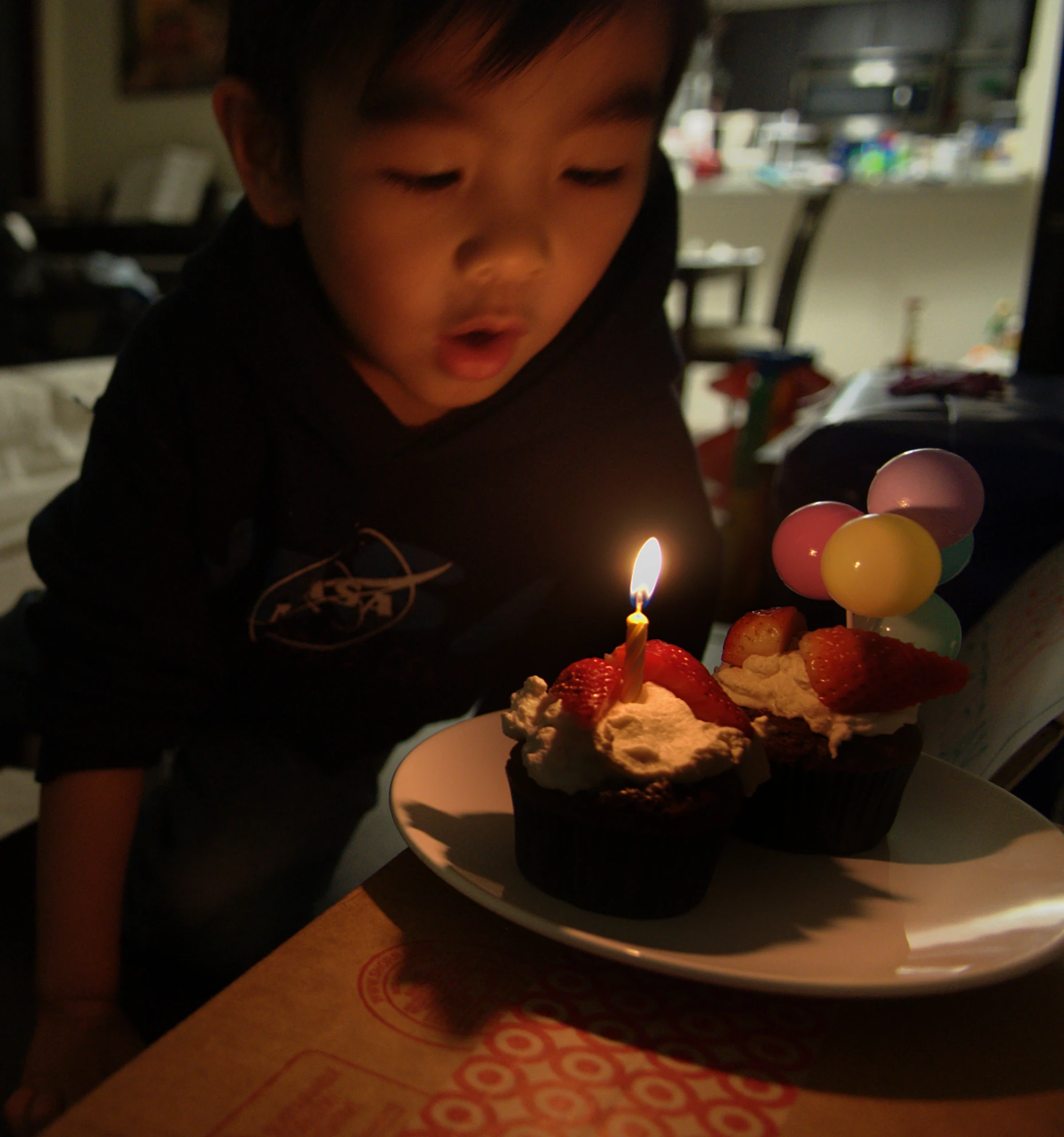 the boy is blowing out the candles on his cupcake