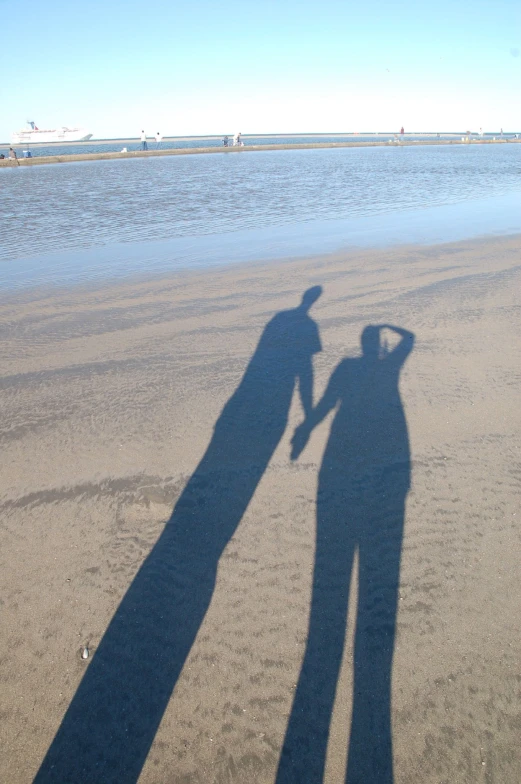 a woman standing on a sandy beach next to water