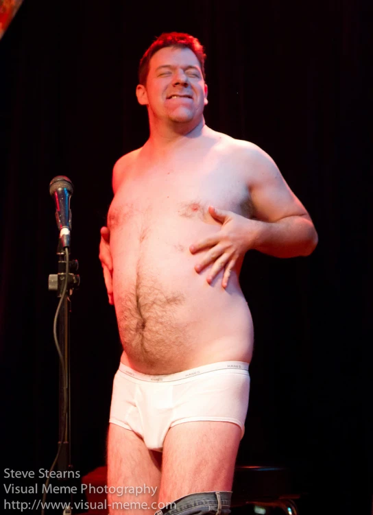 a man in underwear standing next to a microphone