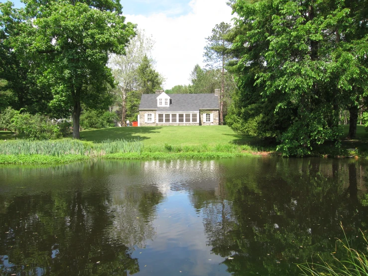 the house is next to the lake and on a tree lined shoreline