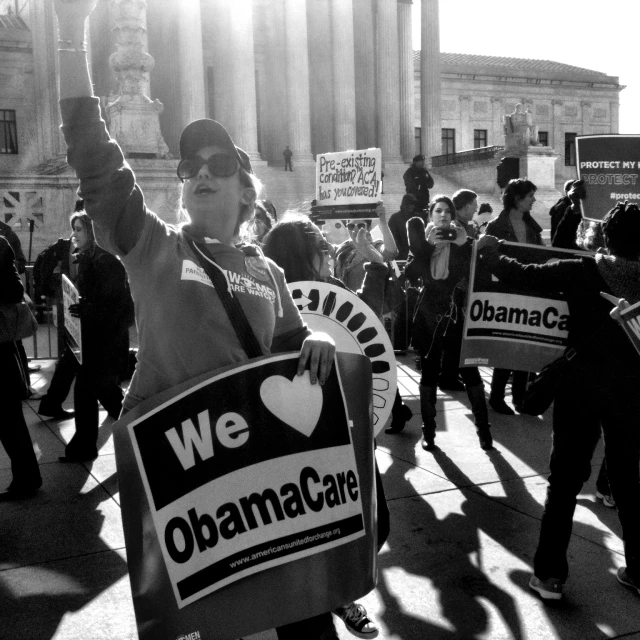 people holding protest signs outside of building with people walking