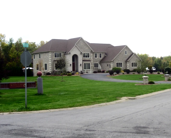 a big house sitting on the corner of a green area