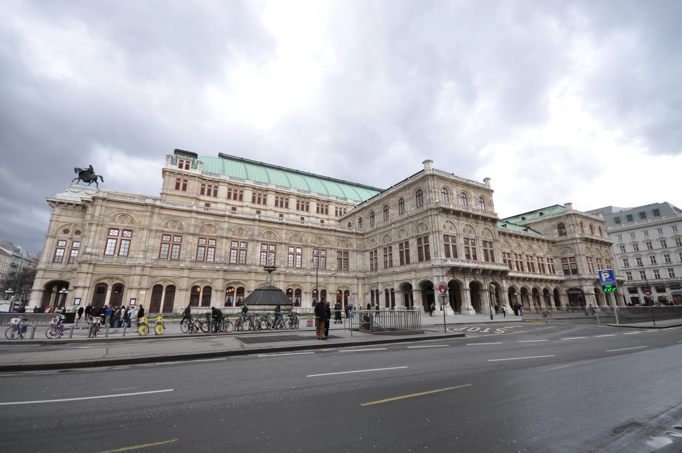 a big building on a street that has a large group of people standing around