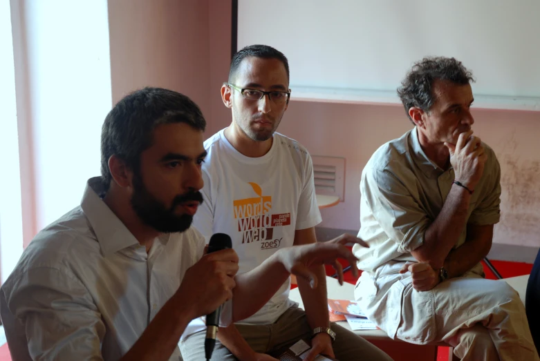 three men in white shirts are sitting down talking