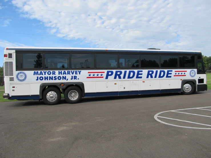 a large bus driving down a road with one bus stopped at it's side