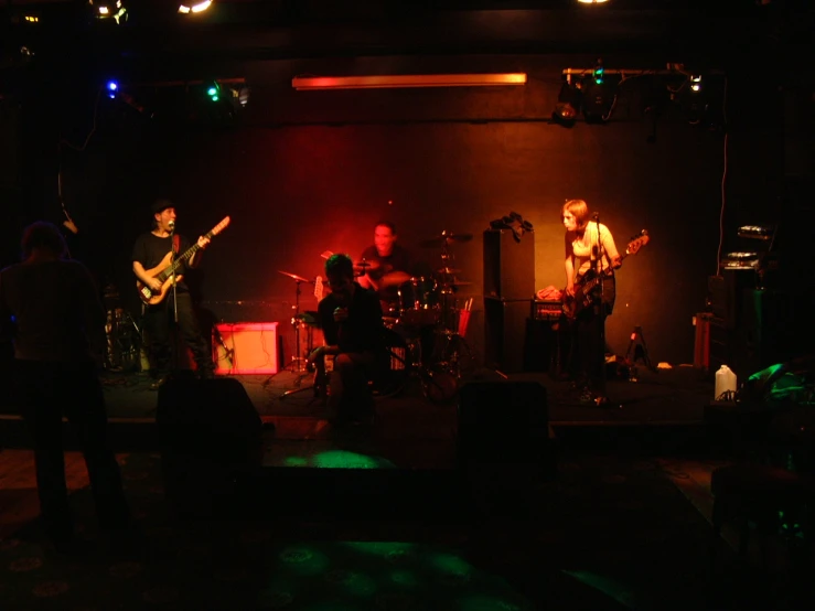 three musicians on stage performing in a dark room