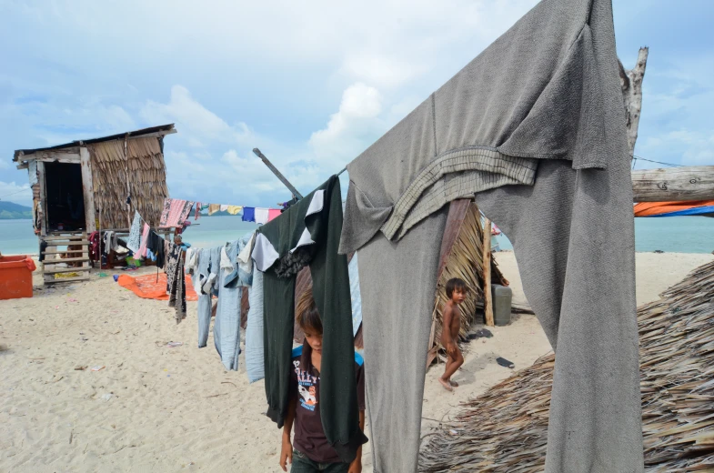 a man standing in the sand by some clothes