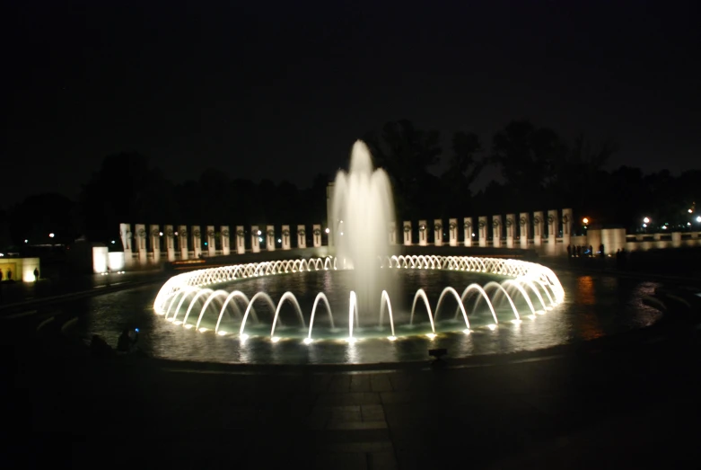 illuminated fountains in a square with trees on each side