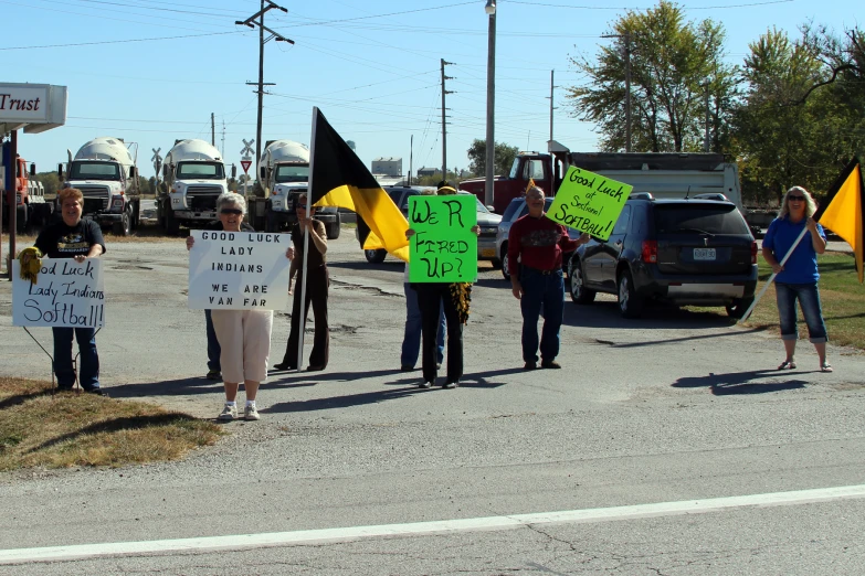 people holding signs on a city street near an oil rig