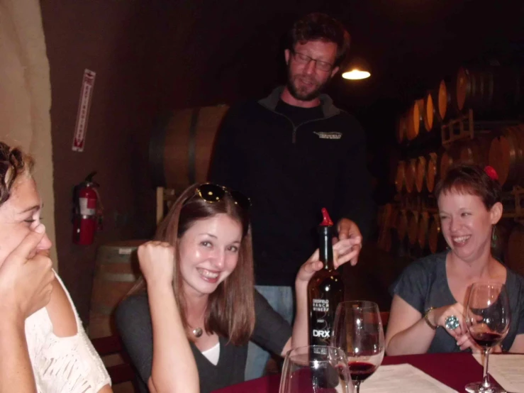 three woman and a man sitting at a table with wine glasses