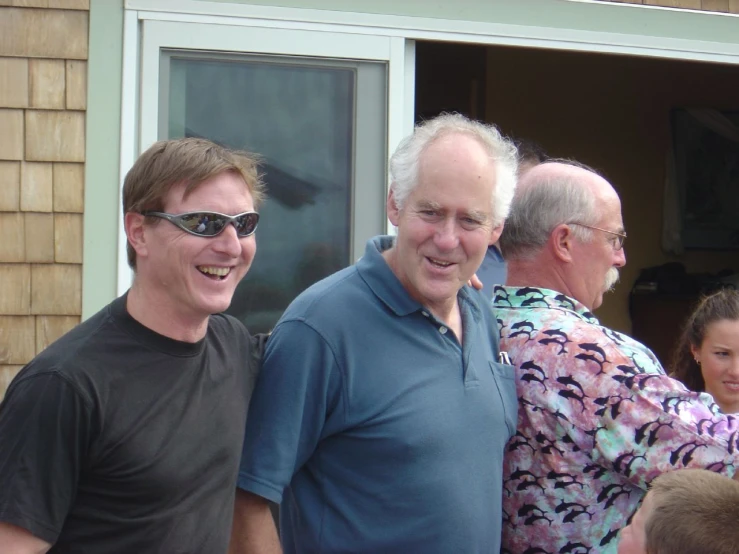 a group of people smile brightly together outside a home