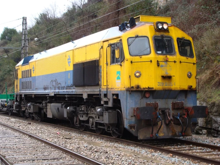 the yellow and blue train engine is traveling down the track