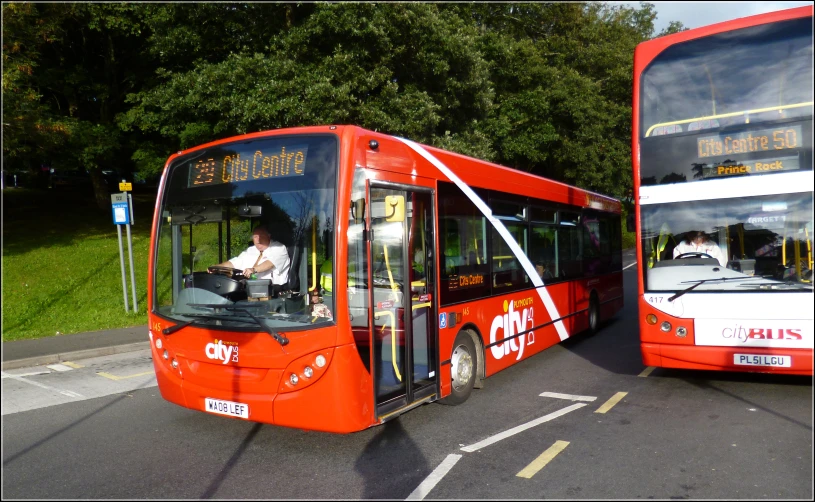 two buses in a parking lot, one with open doors