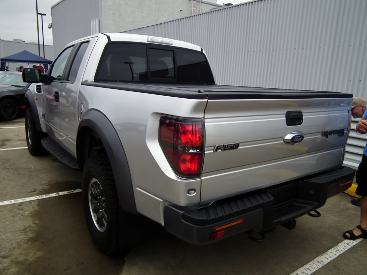 silver truck parked with people picking up the trunk