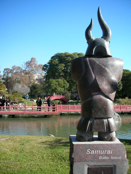statue in grassy area overlooking pond in large park