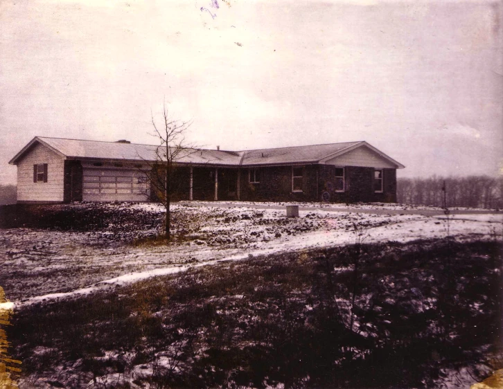 old pograph of two buildings and dirt road with water