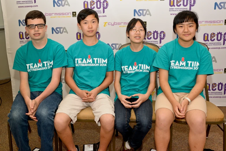 four people wearing teal and blue shirts are sitting together