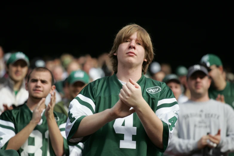 fans applauding young man in green football uniform