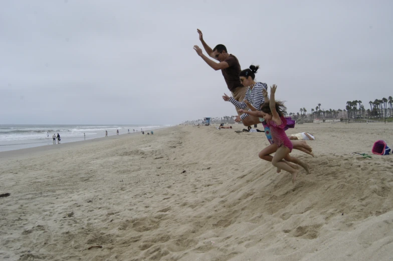 two people are jumping up in the air on a beach