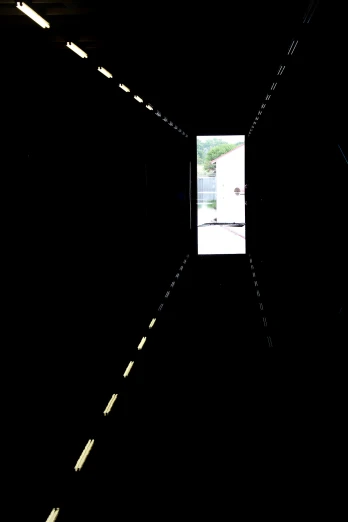 a dark tunnel with bright spots and a picture window