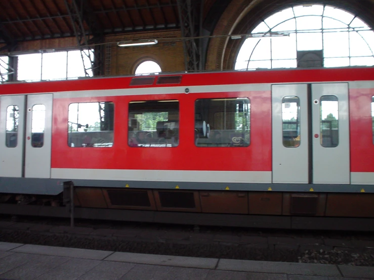 red and white subway train sitting inside of a station