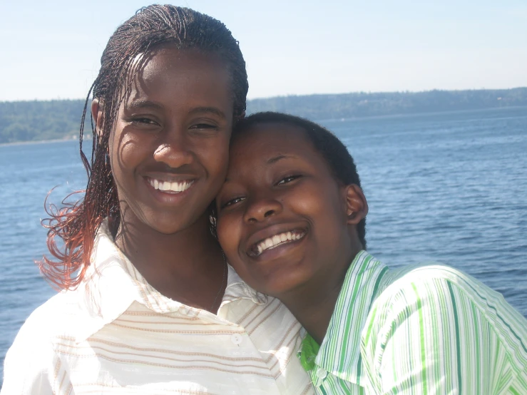 two women stand next to each other near water