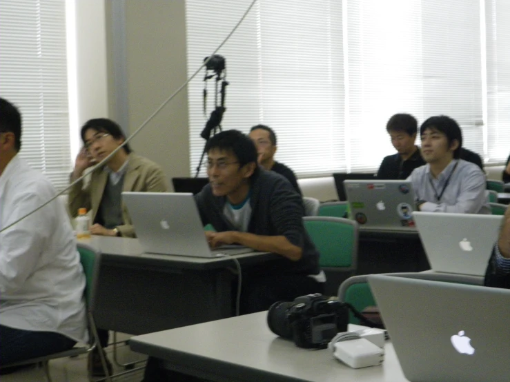 several people sit at computers in rows on desks