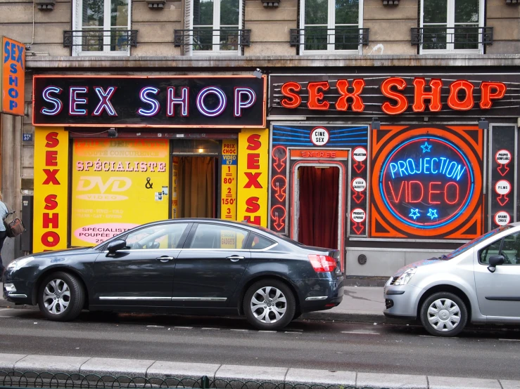 two cars parked in front of an sex shop