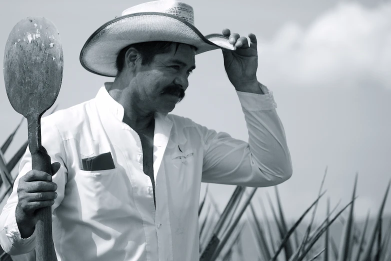 a man wearing a cowboy hat while holding up a paddle